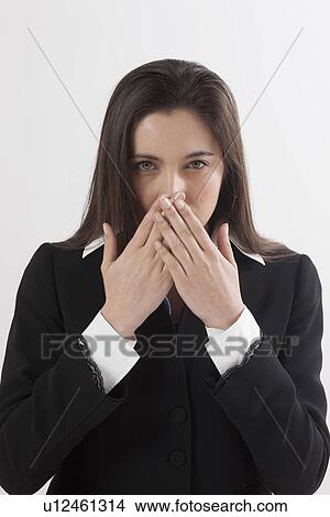 Portrait of young woman with hands covering lips, studio shot View Large Photo Image Picture - Portrait of young woman with hands covering lips, studio shot. Fotosearch