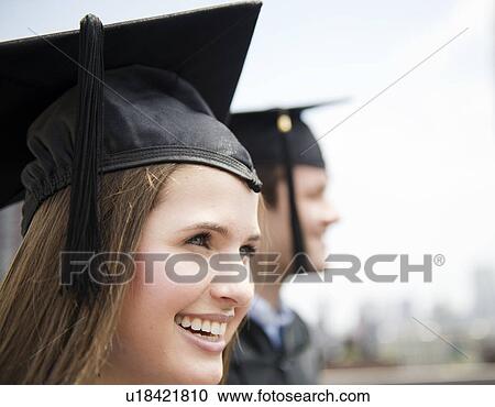 Stock Image - Profiles of young man and woman wearing graduation gowns. Fotosearch