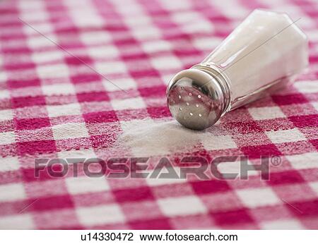 Stock Image - Salt shaker on checked tablecloth. Fotosearch