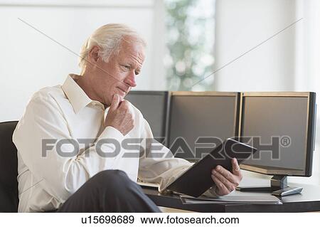 Stock Photo - Senior man using tablet pc. Fotosearch