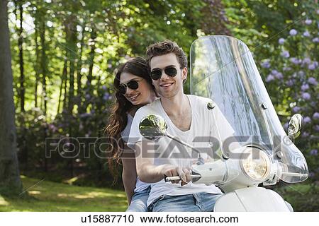 Stock Image - Smiling couple on scooter. Fotosearch
