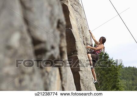 Picture - Smiling woman rock climbing. Fotosearch