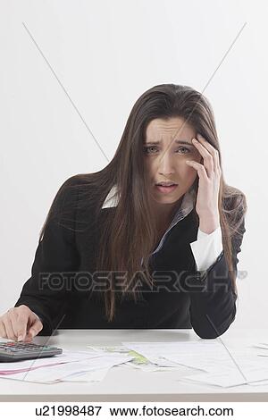 Stock Photo - Studio shot of businesswoman with calculator and bills. Fotosearch