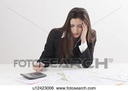 Stock Photograph - Studio shot of businesswoman with calculator and bills. Fotosearch