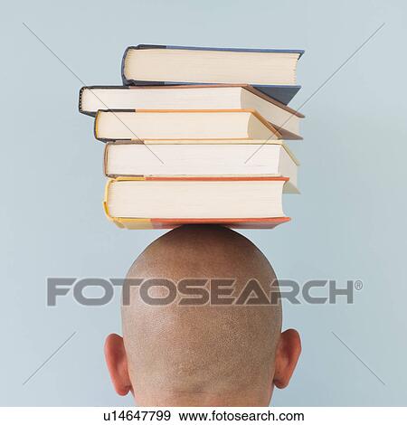 Stock Photo - Studio shot of man with stack of books on head. Fotosearch