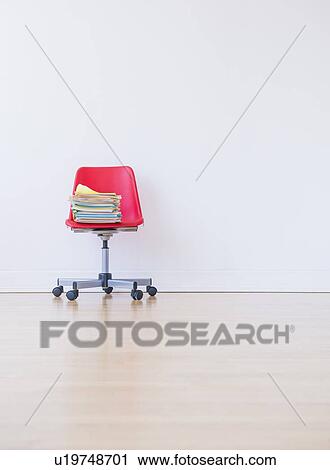 Stock Image - Studio shot of stack of books on red office chair. Fotosearch