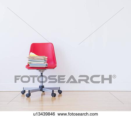 Stock Photograph - Studio shot of stack of books on red office chair. Fotosearch