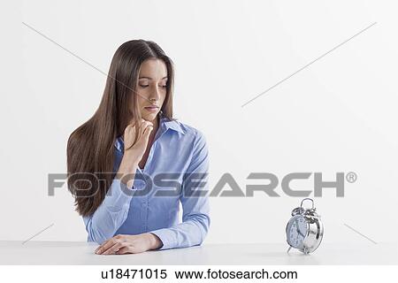Studio shot of woman looking at alarm clock View Large Photo Image Stock Photography - Studio shot of woman looking at alarm clock. Fotosearch