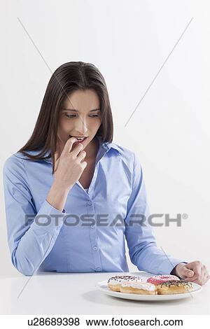 Stock Photo - Studio shot of woman looking at donuts. Fotosearch
