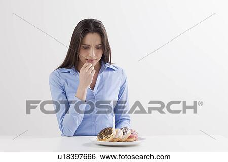 Studio shot of woman looking at donuts View Large Photo Image Stock Photograph - Studio shot of woman looking at donuts. Fotosearch