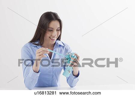 Stock Image - Studio shot of woman opening present. Fotosearch