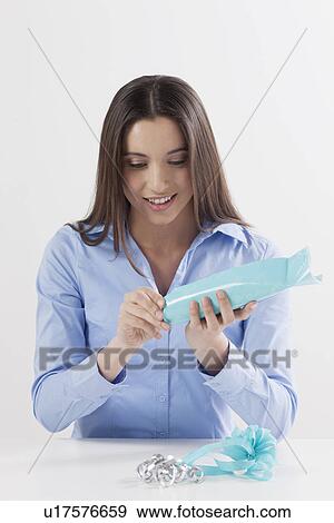 Stock Photo - Studio shot of woman opening present. Fotosearch