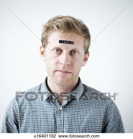 Stock Image - Studio shot of young man with word 'lonely' on forehead. Fotosearch