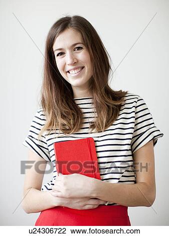 Studio shot of young woman holding book View Large Photo Image Stock Image - Studio shot of young woman holding book. Fotosearch