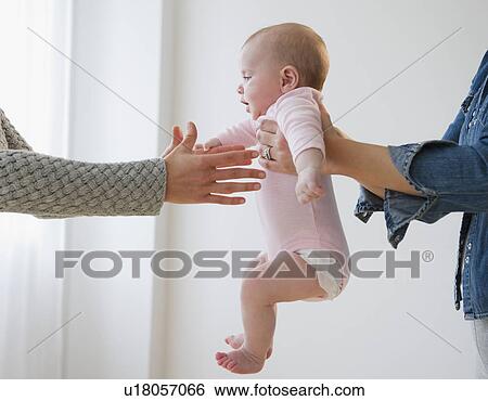 Stock Photograph - Two women holding baby boy (2-5 months) . Fotosearch