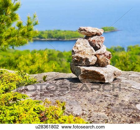 Stock Image - USA, Maine, Camden, Pile of stones and scenic coastline . Fotosearch
