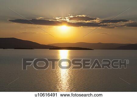 Stock Image - USA, Montana, Flathead Lake, View of sunset over lake. Fotosearch