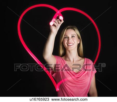 Woman drawing heart on black background View Large Photo Image Stock Image - Woman drawing heart on black background. Fotosearch