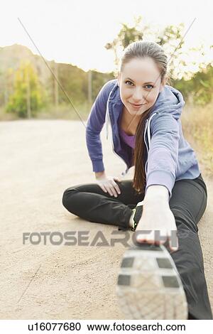 Stock Image - Woman exercising on dusty track. Fotosearch