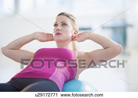 Stock Image - Woman exercising on fitness ball. Fotosearch