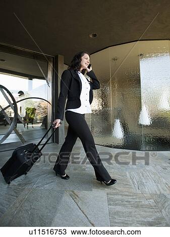 Stock Image - Woman leaving house with piece of luggage. Fotosearch