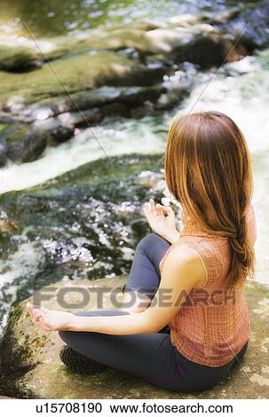 Stock Image - Woman practicing joga in forest. Fotosearch