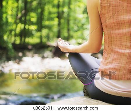 Stock Image - Woman practicing joga in forest. Fotosearch