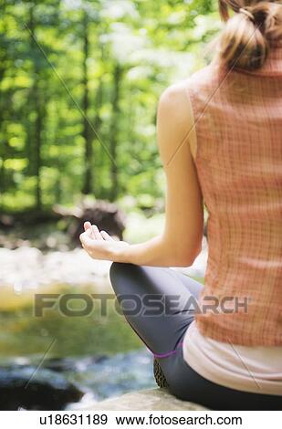 Stock Photo - Woman practicing joga in forest. Fotosearch
