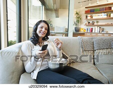 Woman sitting on couch with bowl of popcorn View Large Photo Image Picture - Woman sitting on couch with bowl of popcorn. Fotosearch