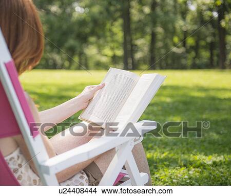 Woman sitting on deck chair and reading book View Large Photo Image Picture - Woman sitting on deck chair and reading book. Fotosearch