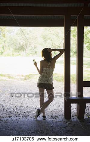 Woman texting on mobile phone standing in hut View Large Photo Image Stock Photograph - Woman texting on mobile phone standing in hut. Fotosearch