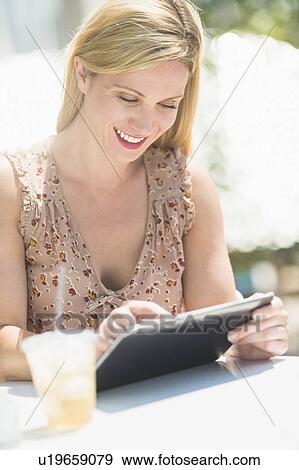 Woman using tablet pc at outdoor cafe table View Large Photo Image Stock Photo - Woman using tablet pc at outdoor cafe table. Fotosearch