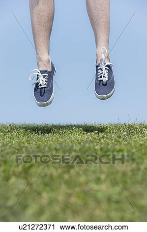 Stock Image - Woman's legs above meadow. Fotosearch