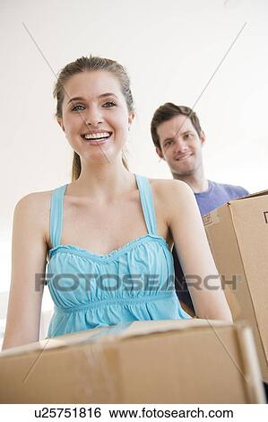 Stock Photograph - Young couple holding cardboard boxes. Fotosearch
