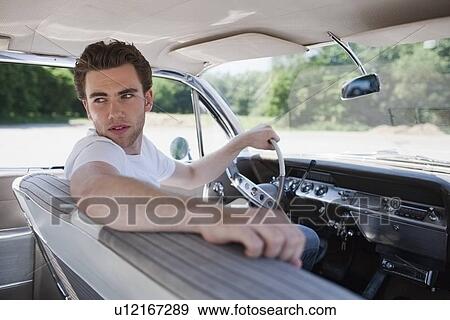 Stock Photo - Young man in vintage car. Fotosearch