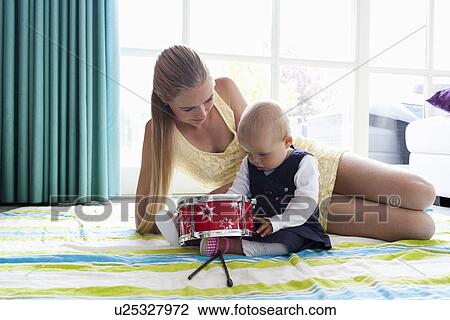 Stock Image - Young mother with daughter playing with drum. Fotosearch