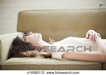 Young woman lying on sofa View Large Photo Image Stock Image - Young woman lying on sofa. Fotosearch