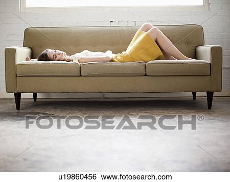Young woman lying on sofa View Large Photo Image Stock Photograph - Young woman lying on sofa. Fotosearch