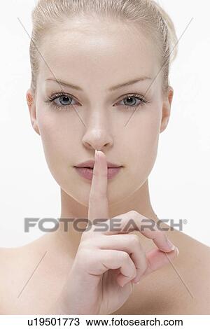 Young woman pressing finger against mouth View Large Photo Image Stock Image - Young woman pressing finger against mouth. Fotosearch
