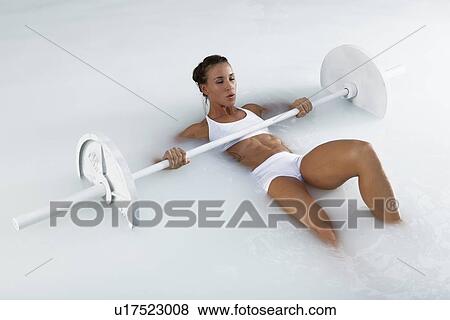 Stock Photo - Young woman weight lifting in water. Fotosearch