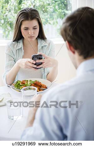 Yung woman texting over meal View Large Photo Image Stock Photo - Yung woman texting over meal . Fotosearch