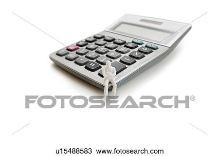 Stock Image - A small dummy figure sitting on a calculator over white background. Fotosearch