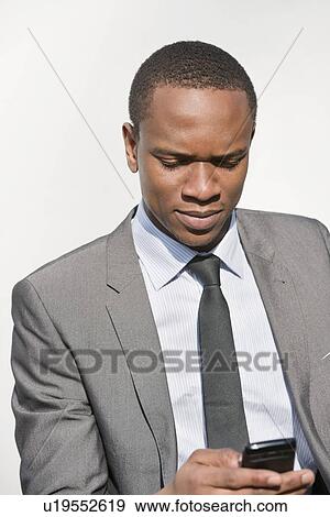 African American businessman text messaging over white background View Large Photo Image Stock Photo - African American businessman text messaging over white background. Fotosearch