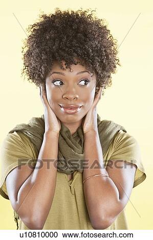 Stock Image - African American woman looking sideways over colored background. Fotosearch