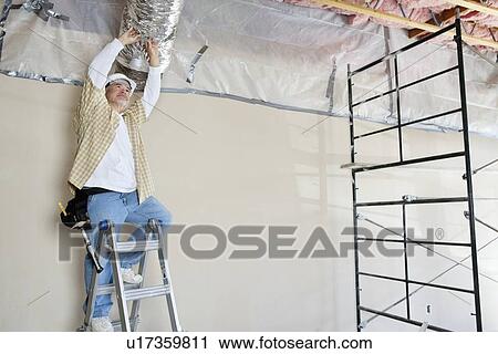 Stock Image - Architect on ladder working on ceiling. Fotosearch
