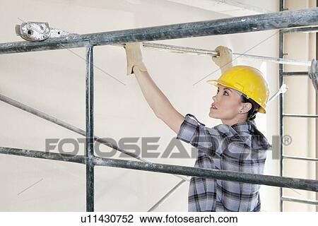 Back view of female contractor placing iron rod on scaffold View Large Photo Image Stock Image - Back view of female contractor placing iron rod on scaffold. Fotosearch