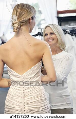 Back view of woman dressed in bridal gown with happy senior owner assisting View Large Photo Image Stock Image - Back view of woman dressed in bridal gown with happy senior owner assisting. Fotosearch