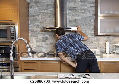 Back view of young man looking at chimney in model home kitchen View Large Photo Image Stock Photograph - Back view of young man looking at chimney in model home kitchen. Fotosearch