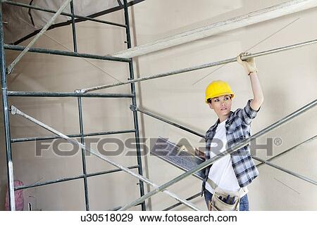 Beautiful female architect looking away while standing under scaffold View Large Photo Image Stock Photo - Beautiful female architect looking away while standing under scaffold. Fotosearch