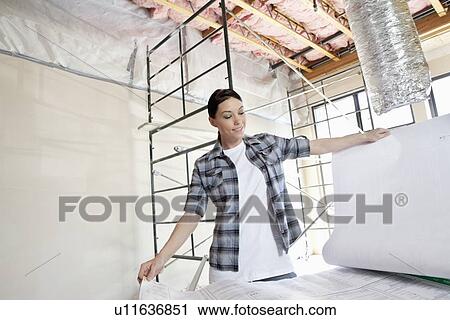 Beautiful mid adult contractor looking at building plans at construction site View Large Photo Image Stock Image - Beautiful mid adult contractor looking at building plans at construction site. Fotosearch
